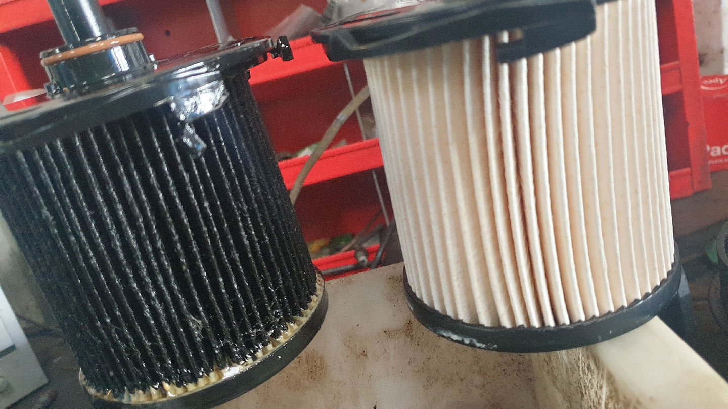 A clogged old fuel filter beside the new one that replaced it