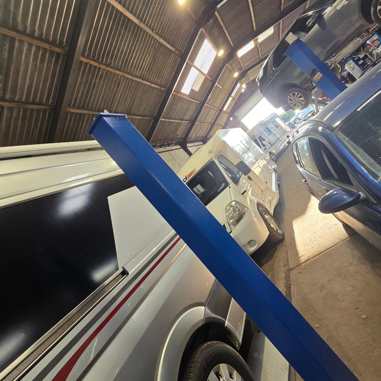 A motorhome beside the lift inside the Manic Mechanic workshop